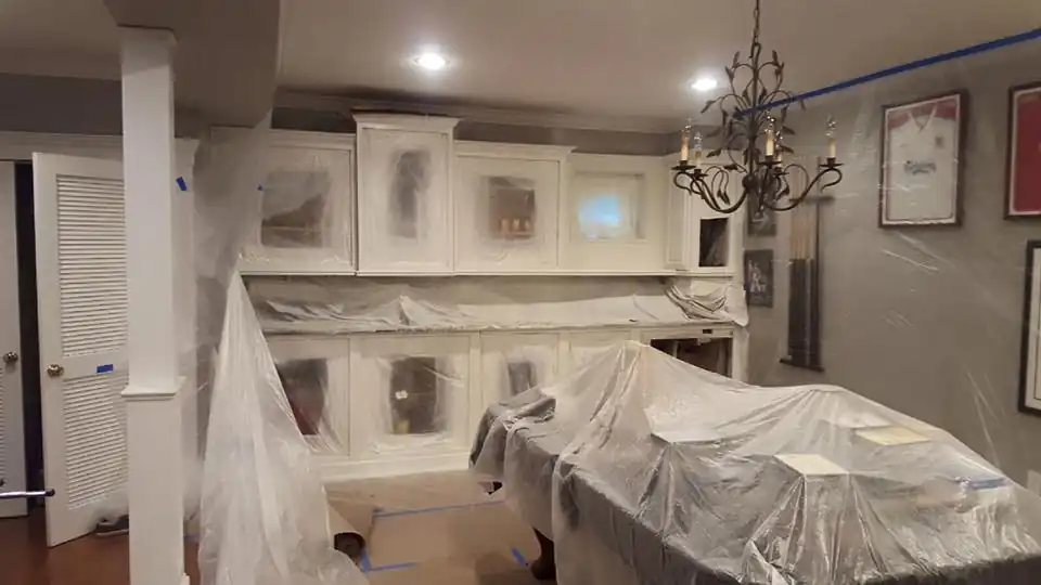 Kitchen cabinets prepped under plastic sheeting before refinishing