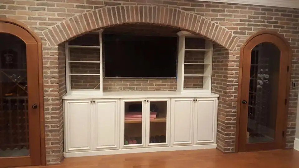 White refinished built-in cabinets and shelving set inside an arched brick wall