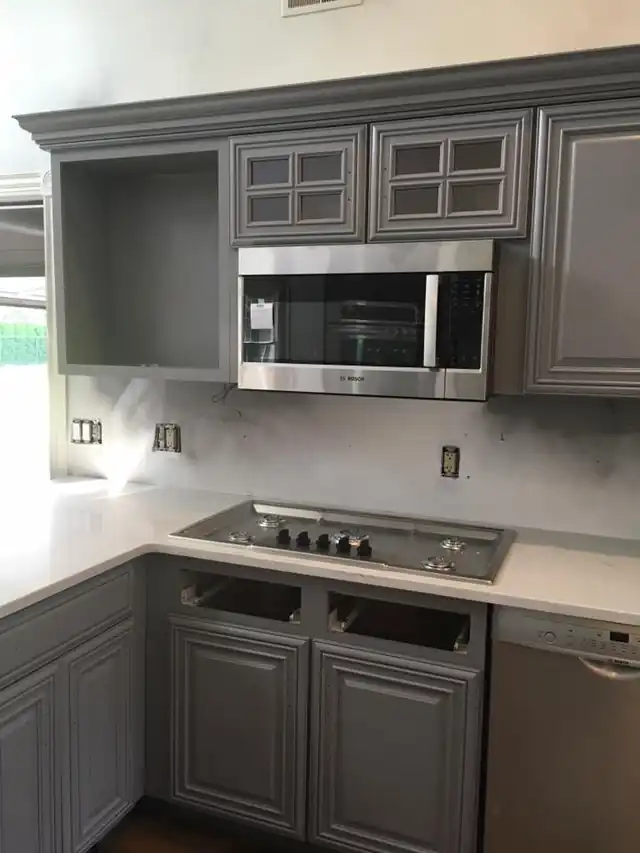 Gray cabinets with a microwave cabinet above a white counter