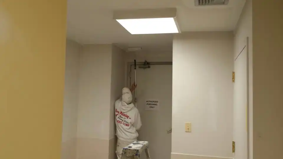 Commercial hallway with a painter seen from behind
