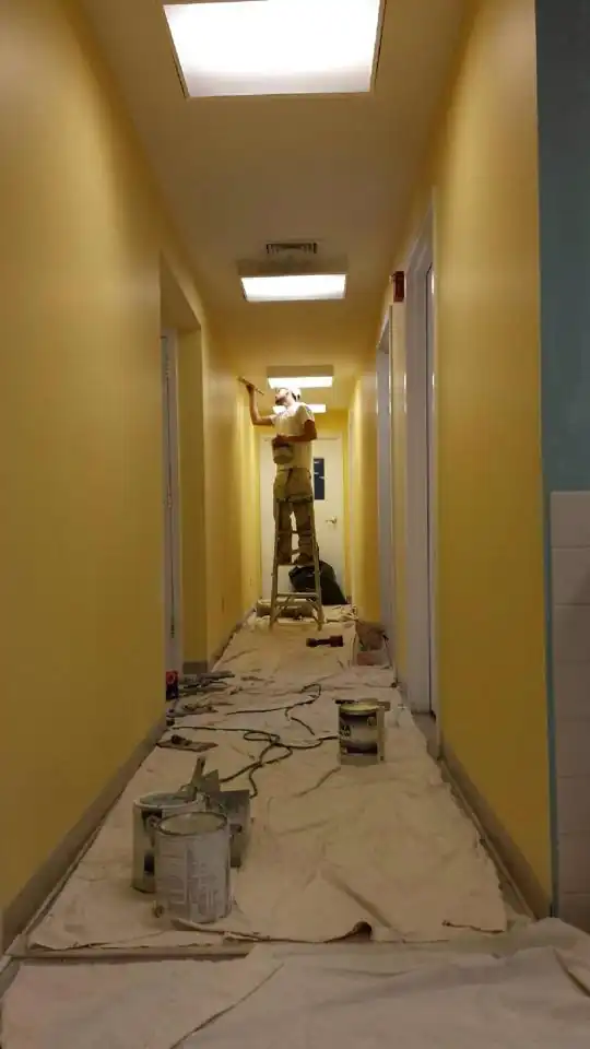 Yellow commercial corridor with drop cloths on the floor