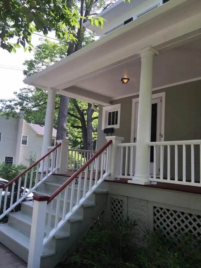 White porch and railing above red-stained steps and deck boards