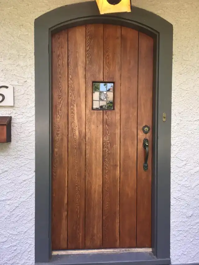 Arched wood front door with a stained finish