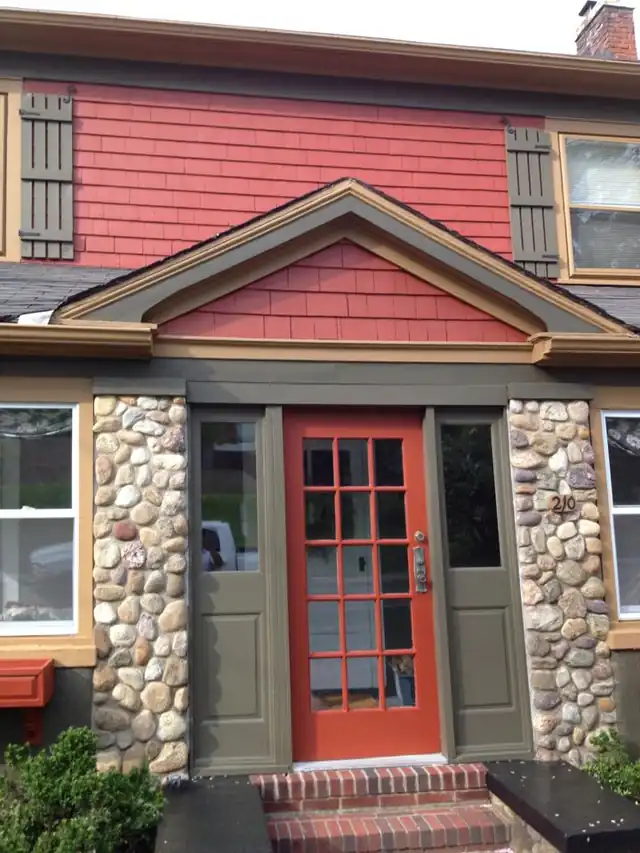 Red shingle house with a stone front, a red door and gray trim