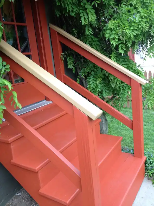 Exterior stair painted red-orange with a white rail