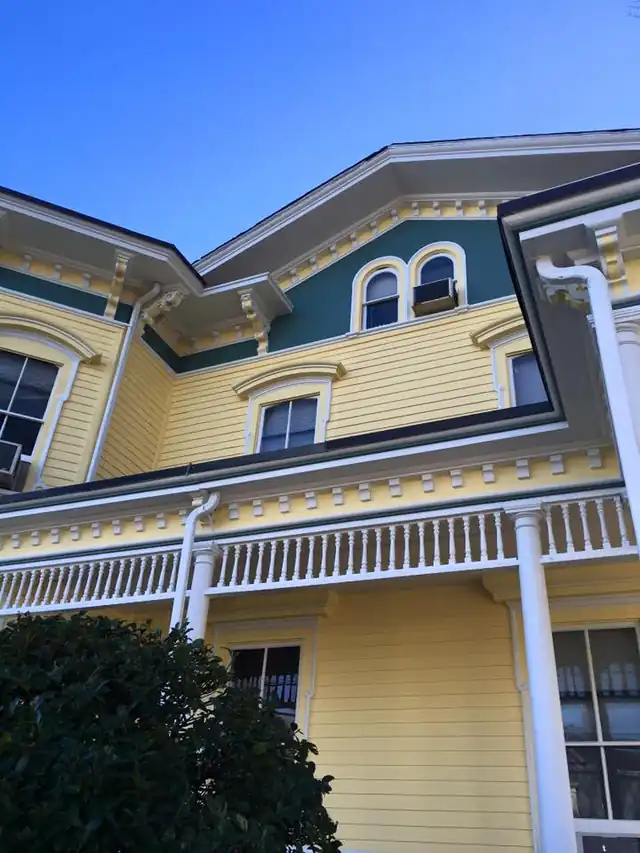 Finished yellow Italianate Victorian with a teal panel and white brackets