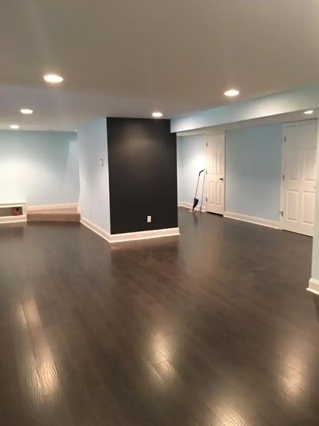 Second view of the finished basement, dark wood floor and pale walls