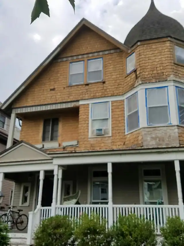 Shingle Victorian with two turrets and a porch, exterior work in progress