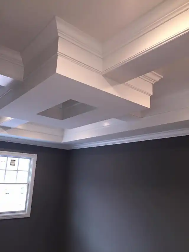Coffered white ceiling over a room painted charcoal gray with crisp white crown moulding
