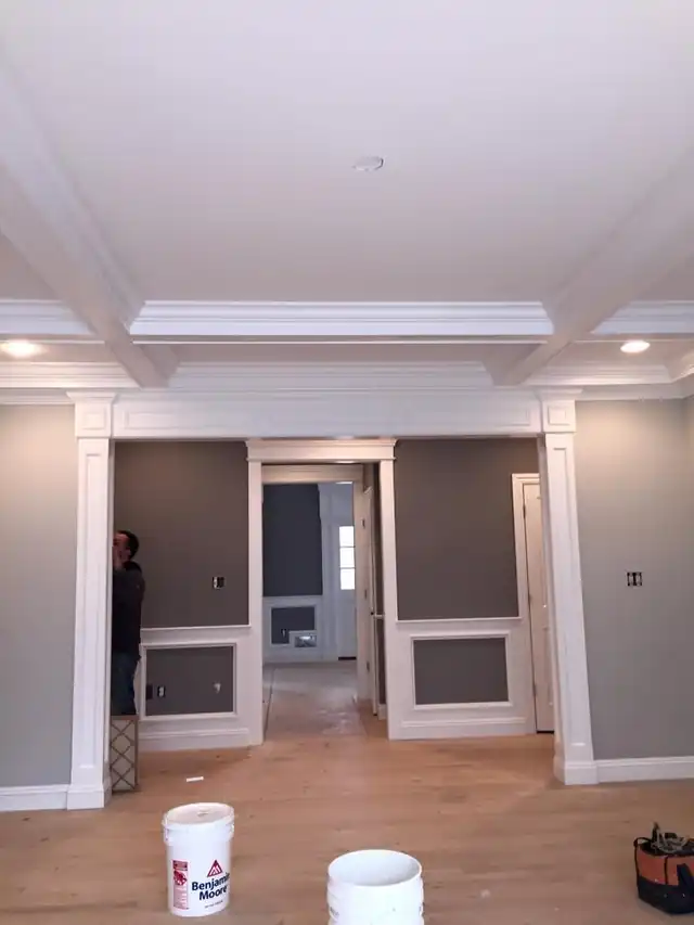Hallway with crown moulding and gray walls, paint buckets standing on the floor