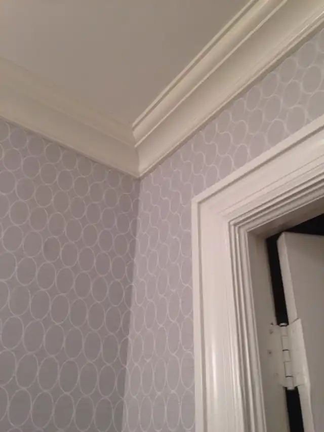 Patterned wallpaper hung above a white chair rail